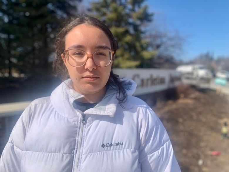 A woman stands outside a university campus.