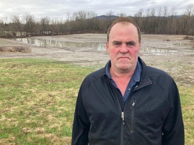 A man stands in front of a flooded field 