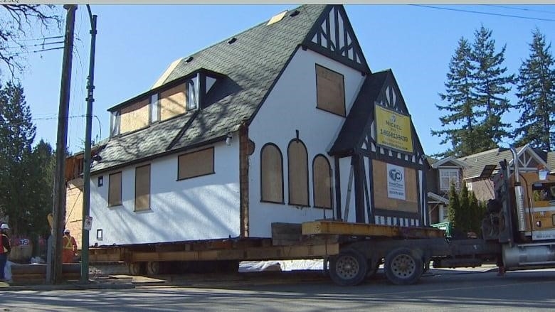 A house being moved by a large truck in Vancouver.