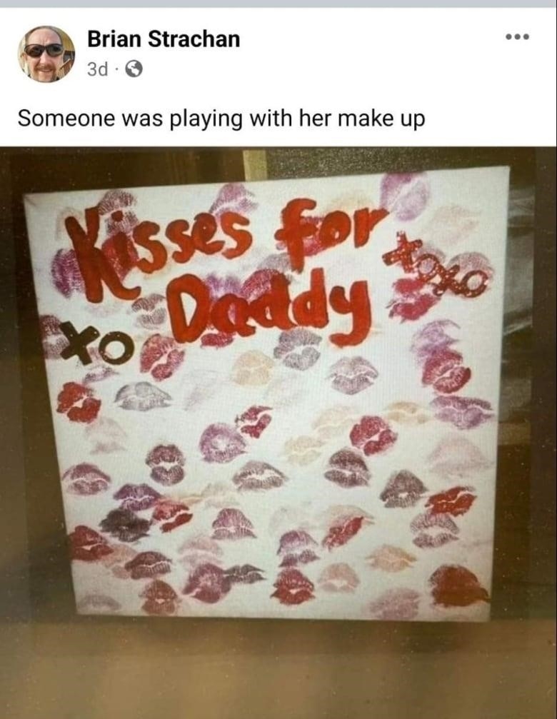 A large square of paper or cardboard is covered with red kiss marks and the hand-written words 'Kisses for Daddy.' 