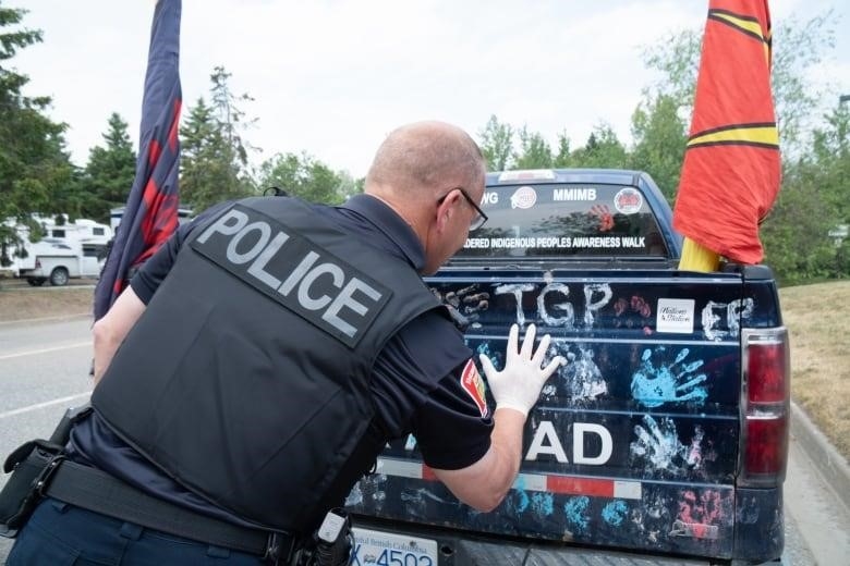 Police Office printing his handprint on the back of the truck.