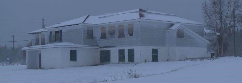 A building sits in the snow. It has many windows. 