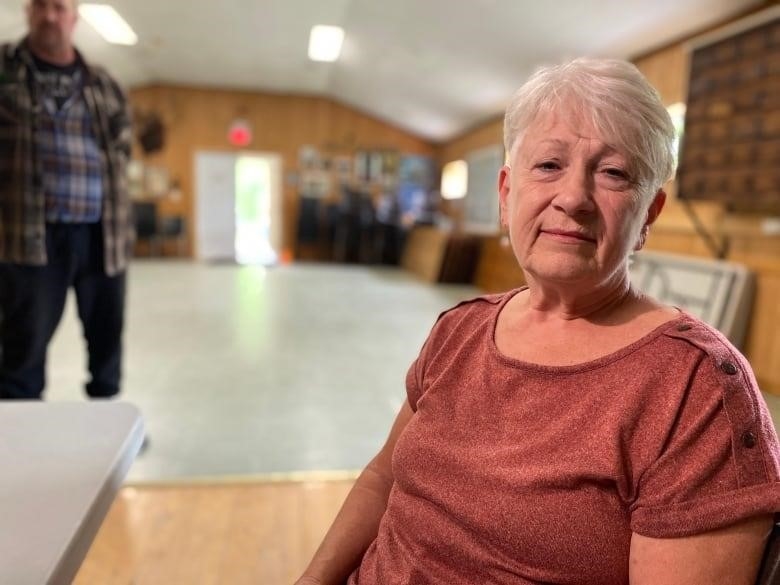 A woman sits inside a community hall. 