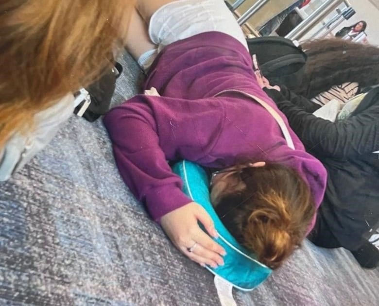 a young teen sleeps on the floor at the airport in Montreal.