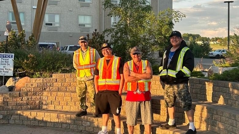 Security guards Edwin Gunn, Ethan Maurice, Dwayne Bourassa and Roger McCallum stand in front of a hotel.