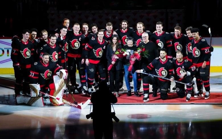 A hockey team poses for a photo with a player's family.