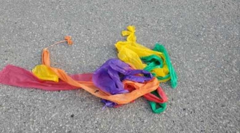 Red, purple, yellow and green plastic ribbons are crumpled in a ball on the ground.