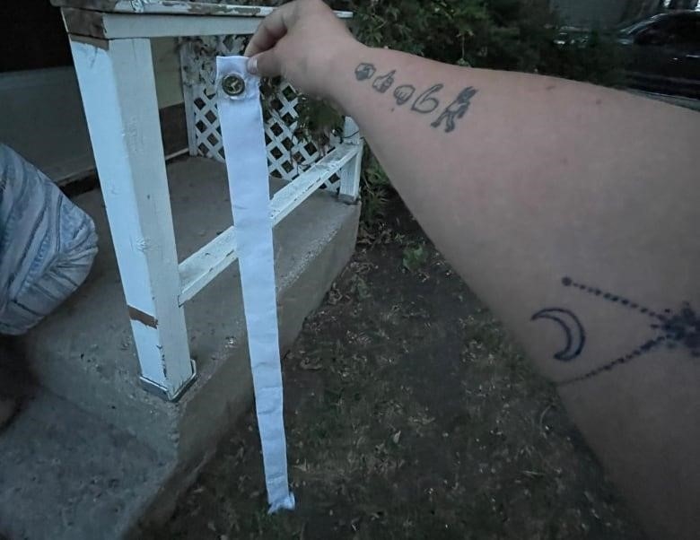 A person holds a white grommet for a flag. 