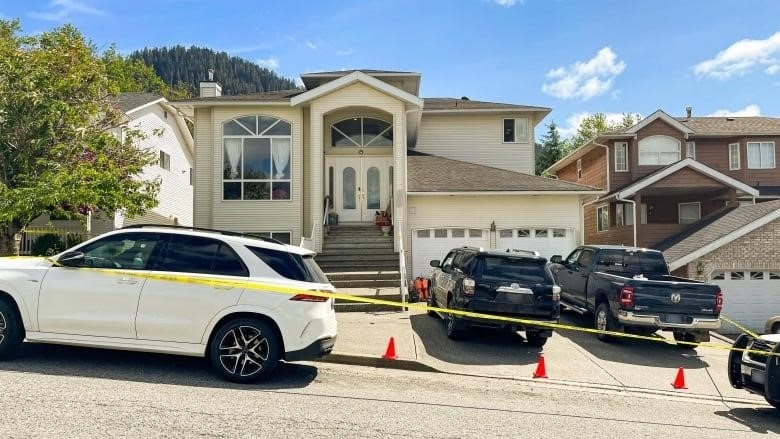 A large family home with a two-car garage is surrounded by police tape. 