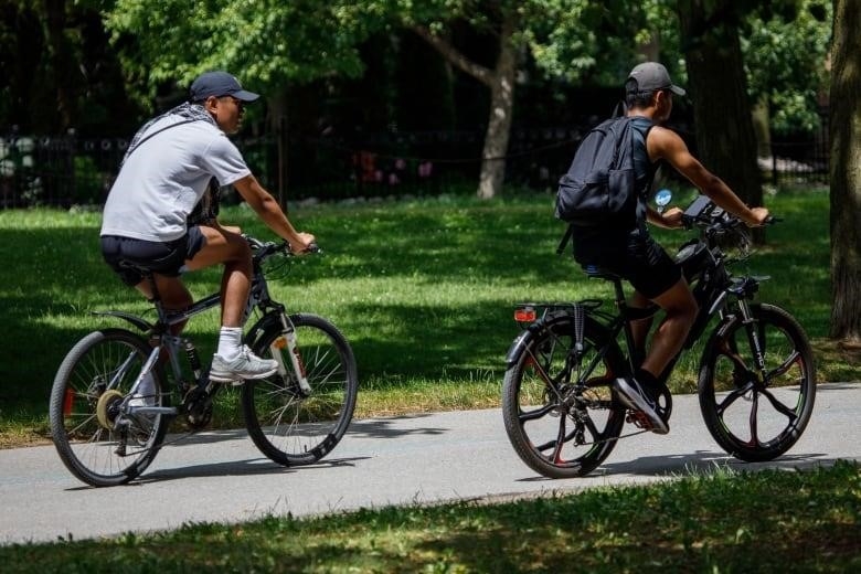 Two cyclists ride along a path at Toronto's Woodbine Beach.