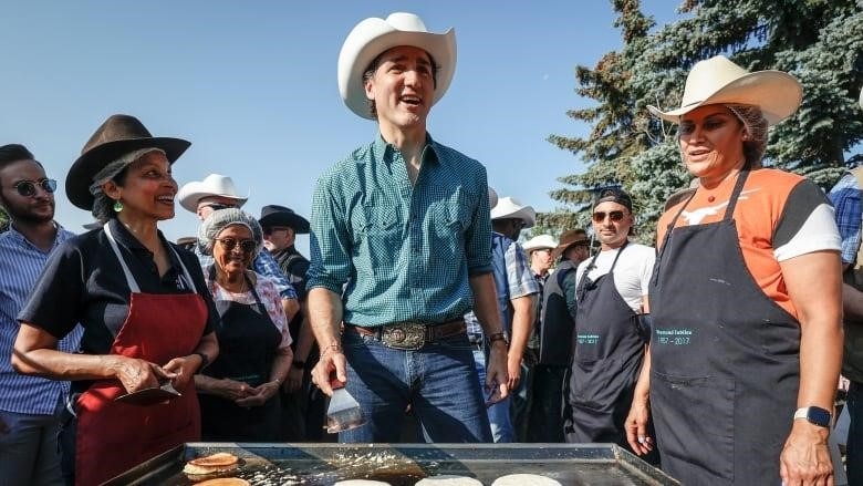 A man wearing a cowboy hat flipping pancakes.