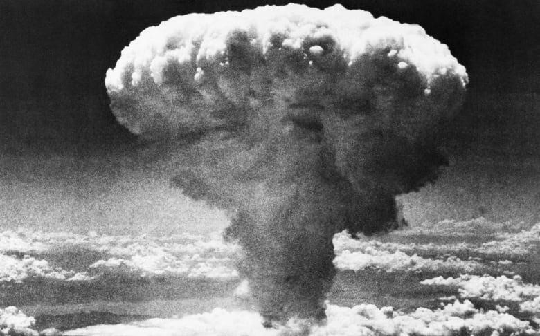 A black-and-white photo shows a mushroom cloud moments after the atomic bomb was dropped on Nagasaki