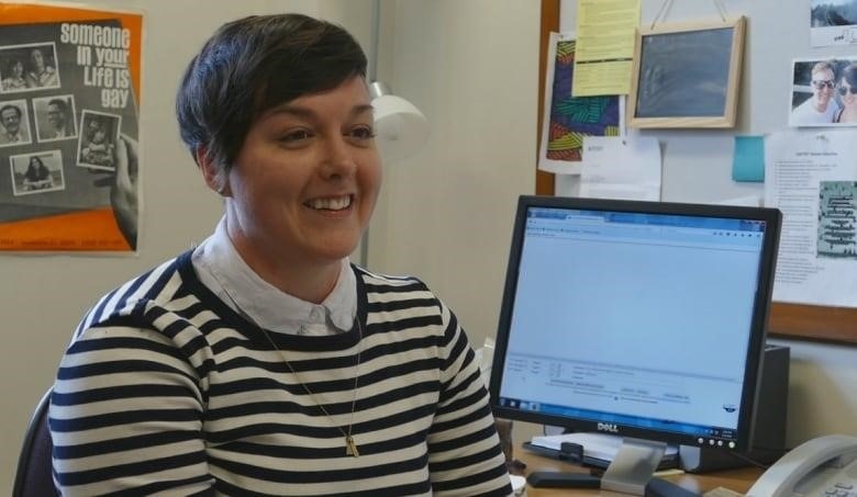 A professor in striped sweater sits facing away from their computer monitor.