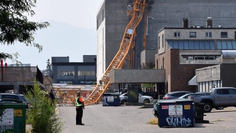 A collapsed yellow crane sits on top of a crushed office building.