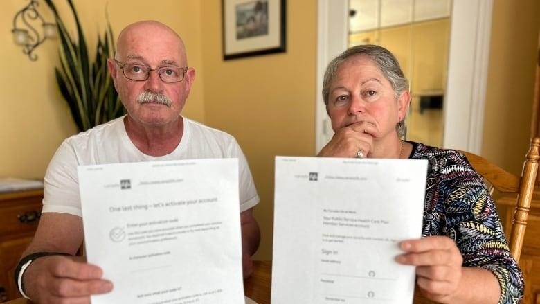 A man and woman hold up papers.