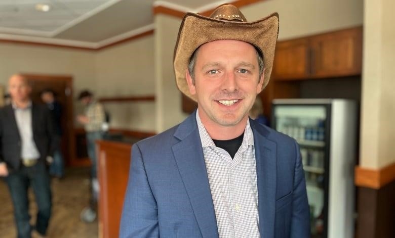 A man in a cowboy hat, blue blazer and button down shirt is pictured inside a private event room at the Calgary Stampde.