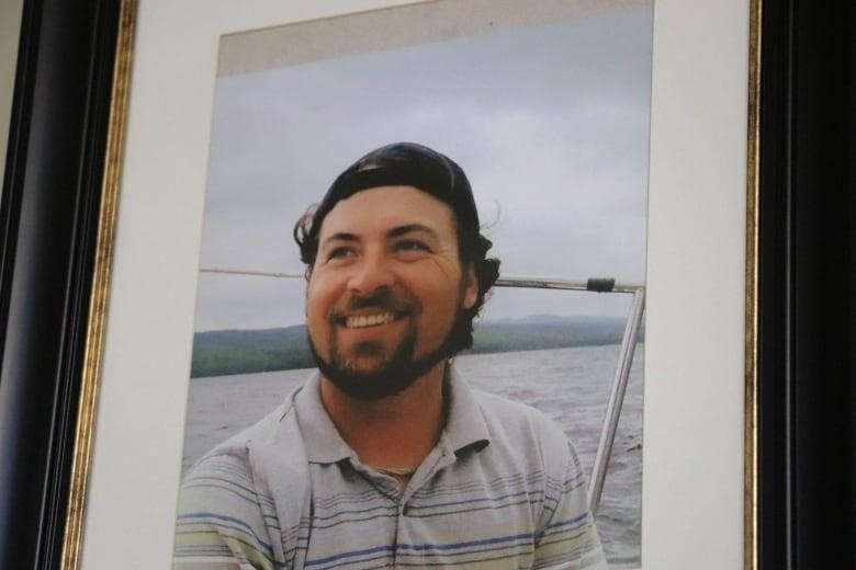 A framed photo of a man smiling, sitting on a boat 