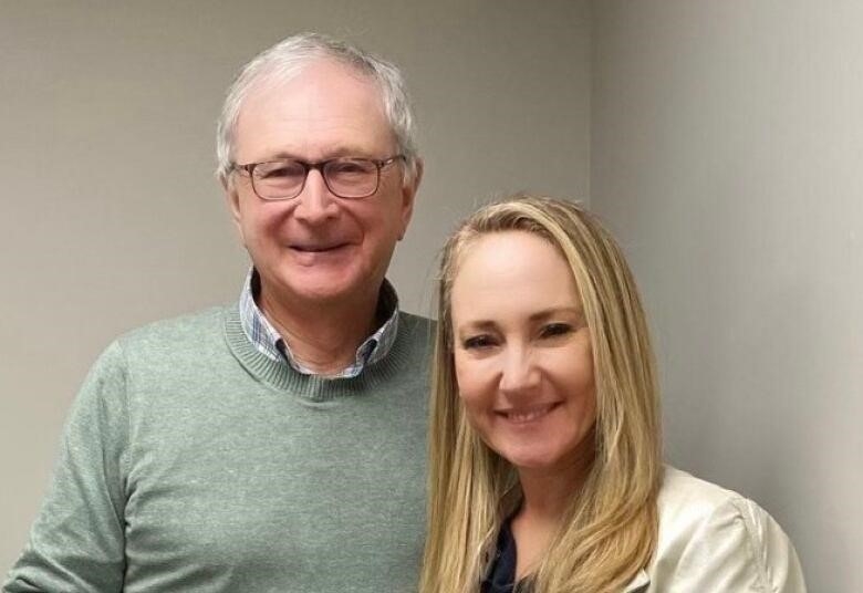 A man with grey hair and glasses posing with a woman with long blond hair