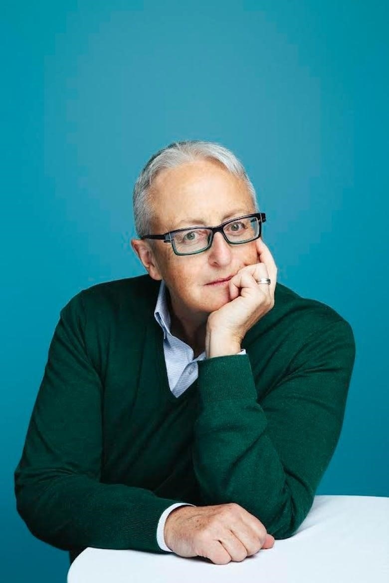 A woman with short hair and glasses looks into the camera for a professional headshot. 