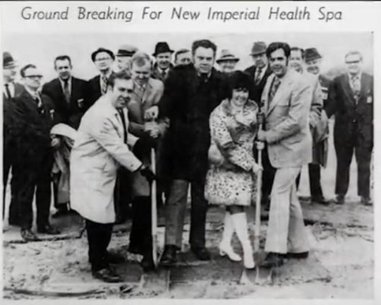 A group of people stand with shovels in their hands, about to break ground. 