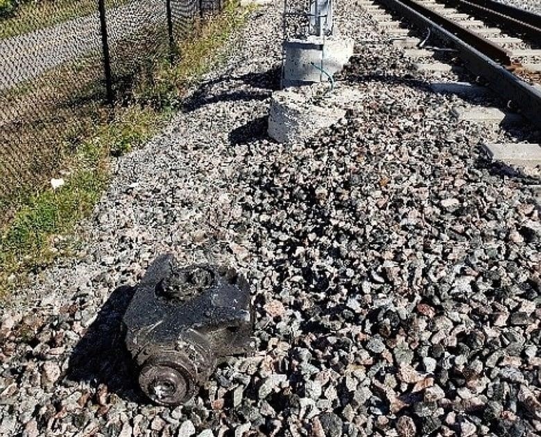 A broken gearbox sits by some railway tracks.