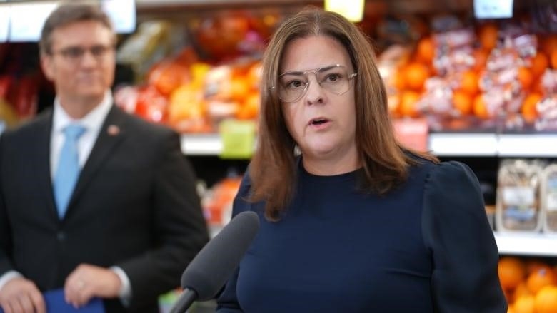 A woman speaks into a microphone inside a grocery store.