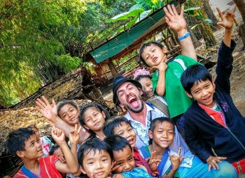 kids smile at the camera, holding up peace signs. 