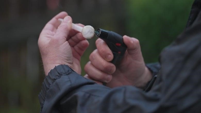 A visitor to a Friday night, pop-up safe site in Cobourg, Ont., prepares a drug pipe. Community reaction to the unsanctioned, volunteer-run operation has been mixed. 