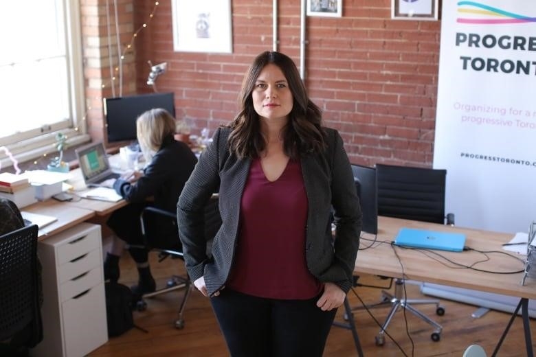 A woman in a business suit stands in an office.