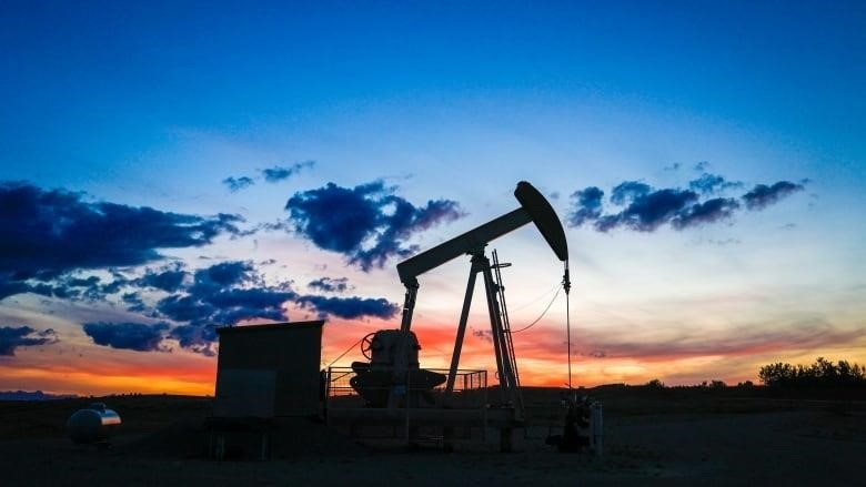 An oil pumpjack is pictured as the sun sets. 