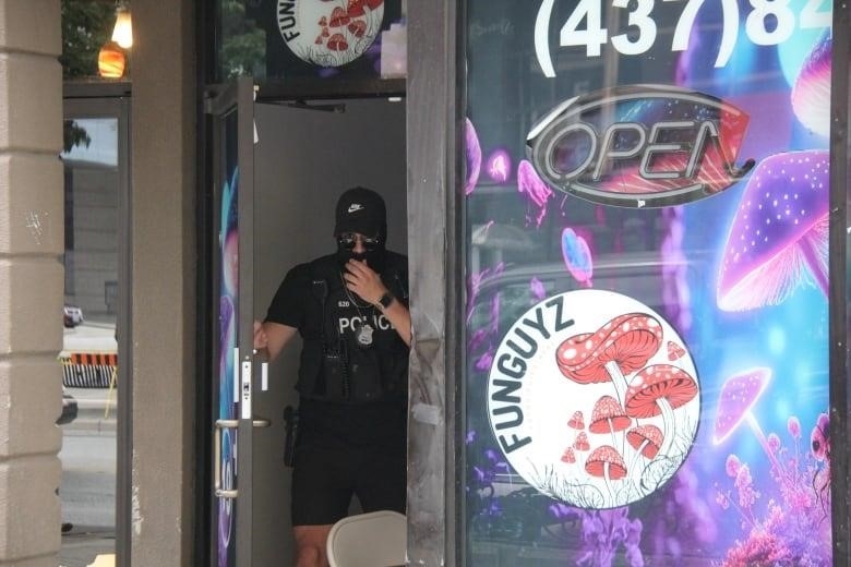 A masked police officer coming out of a store.