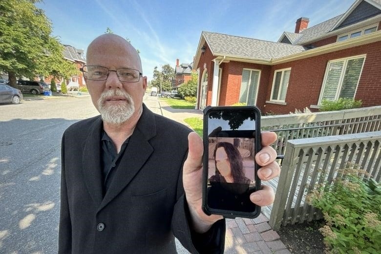Reggie Ferguson shows picture of sister Janet Ferguson outside funeral home in Carleton Place, July 6, 2023