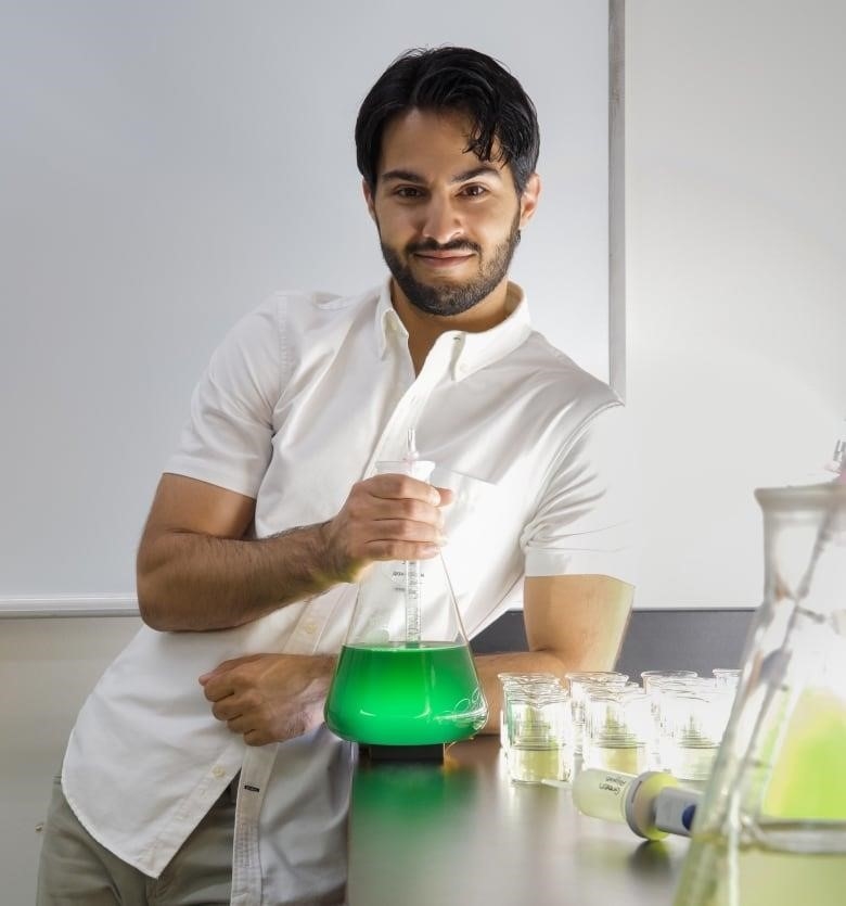 René Shahmohamadloo is an ecotoxicologist and postdoctoral scientist shown holding holding a flask of cyanobacteria.