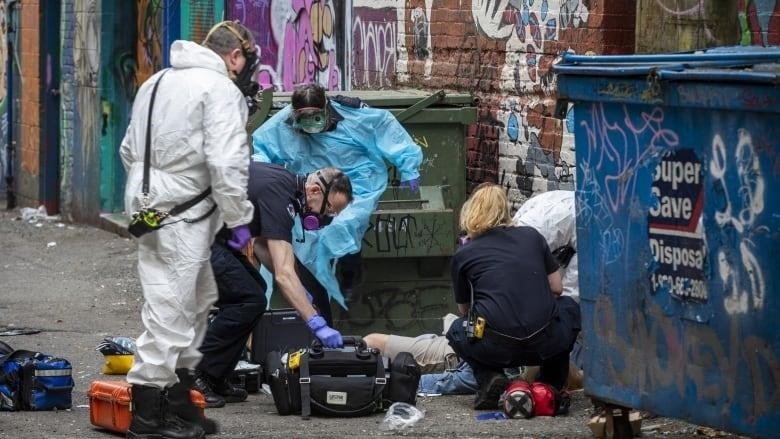 Paramedics and first responders give chest compressions to a person suffering from a suspected overdose in Vancouver, British Columbia alleyway in May 2020. More than 7,300 Canadians died from drug poisonings in 2022.
