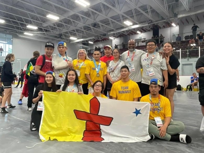 A group of people stand behind the Nunavut flag.