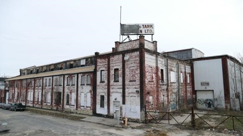 An old building with faded red paint and a sign with most of its letters covered.