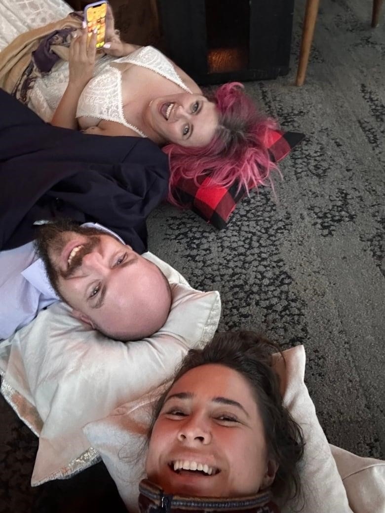 A woman in a wedding dress, and a man in a suit smile in this selfie. 