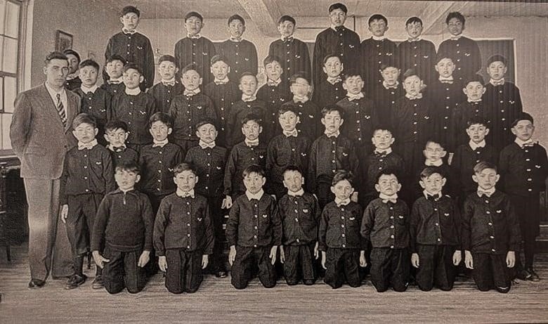 An old black and white photo of former students of the school -- all in uniform in a school picture