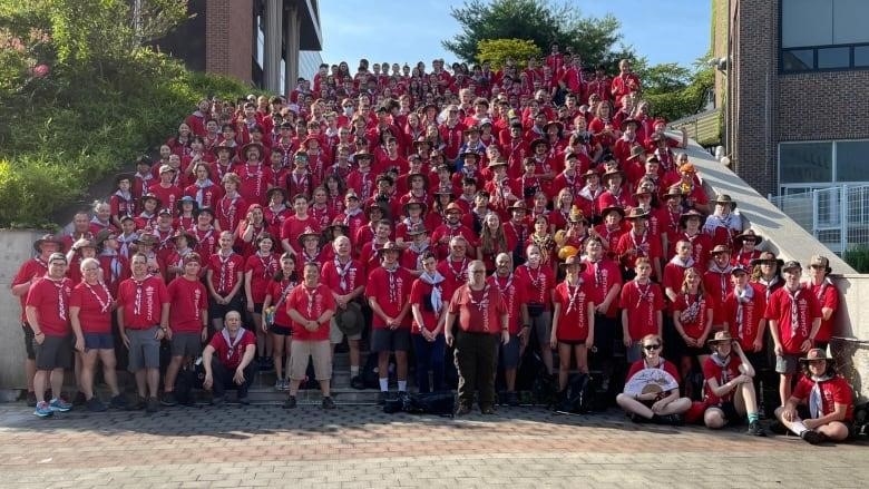 Kids and adults take a group photo outside.