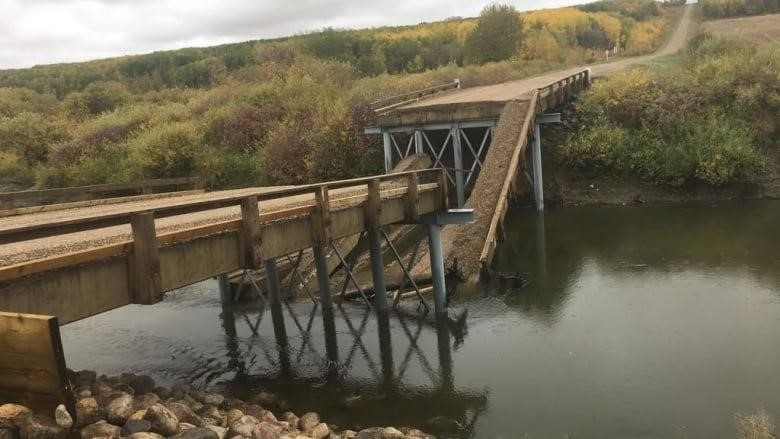 The photo shows the middle section of a bridge over a river which has completely collapsed into the water below.
