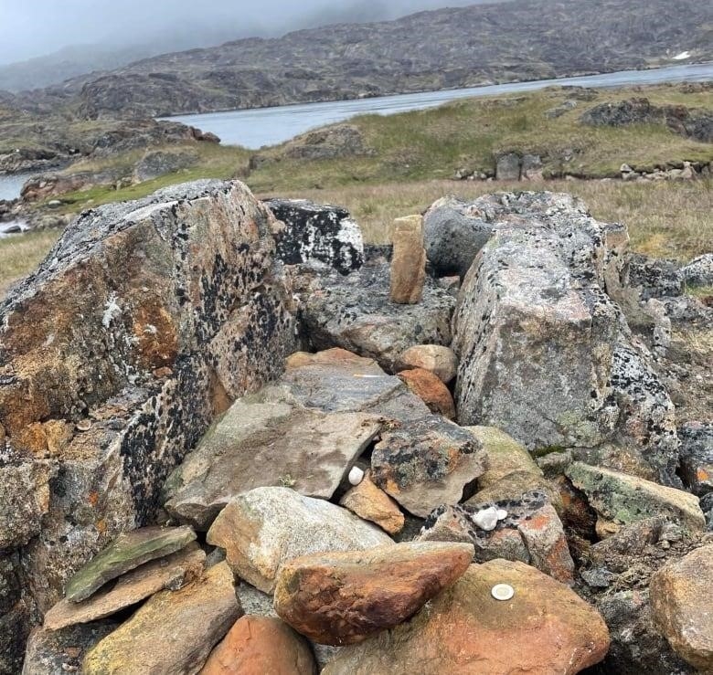 A grave marked by rocks near a shoreline. 