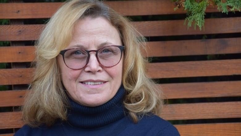 A woman with glasses smiles at the camera.