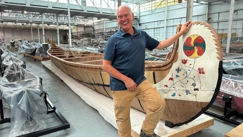 Jeremy Ward poses with a birchbark canoe in the museum's old warehouse. 