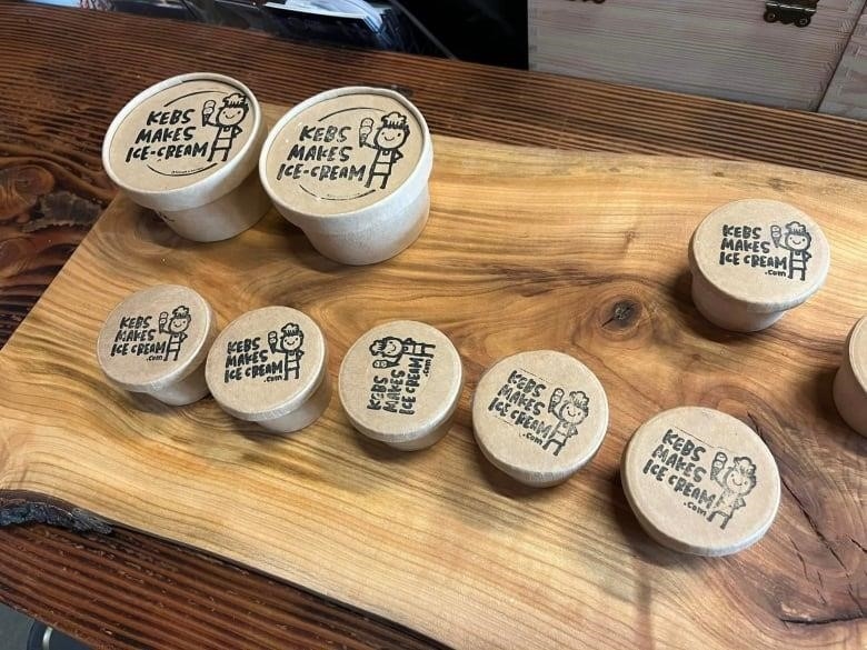 Tubs of ice cream labelled 'Kebs Makes Ice-Cream' laid out on a wooden table.