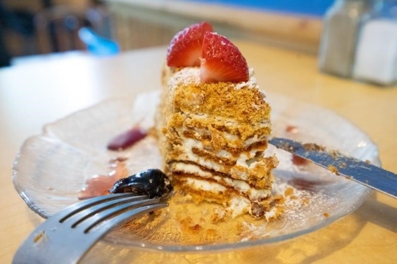 A dessert sits on a plate next to a fork and knife.