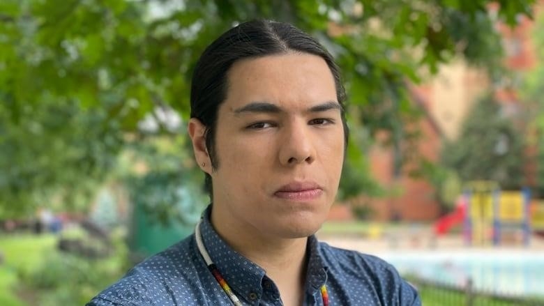 An Anishinaabe man wears a blue shirt with his arms crossed and looks at the camera.