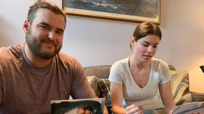 A brother and sister are shown looking over photographs of their father, who died in the recent Nova Scotia floods.