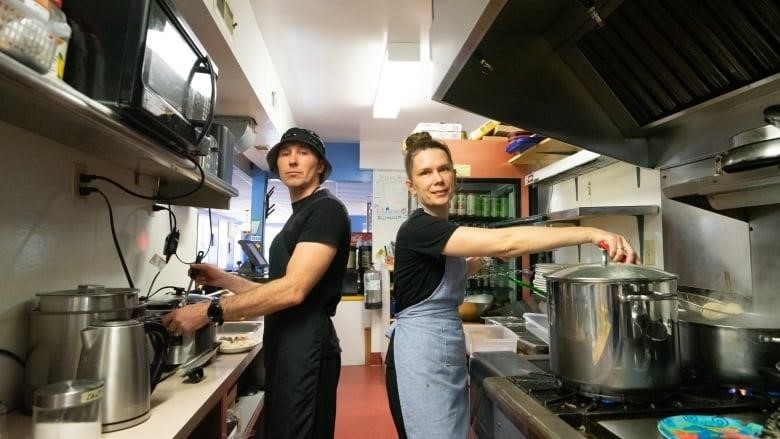 Two people work in a restaurant kitchen.
