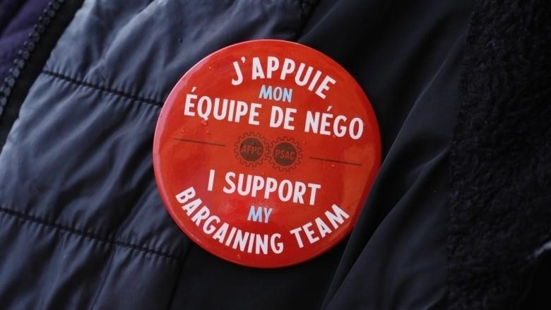 A red button supporting striking workers in both English and French.