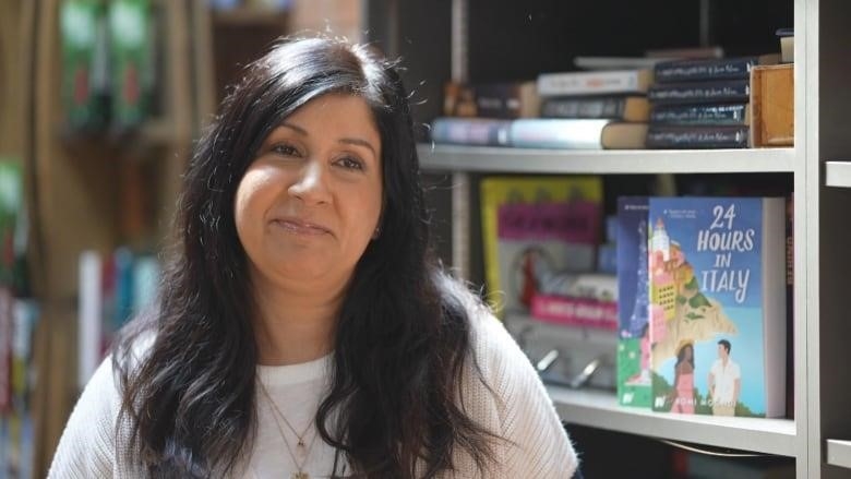 Romi Moondi stands in front of books.